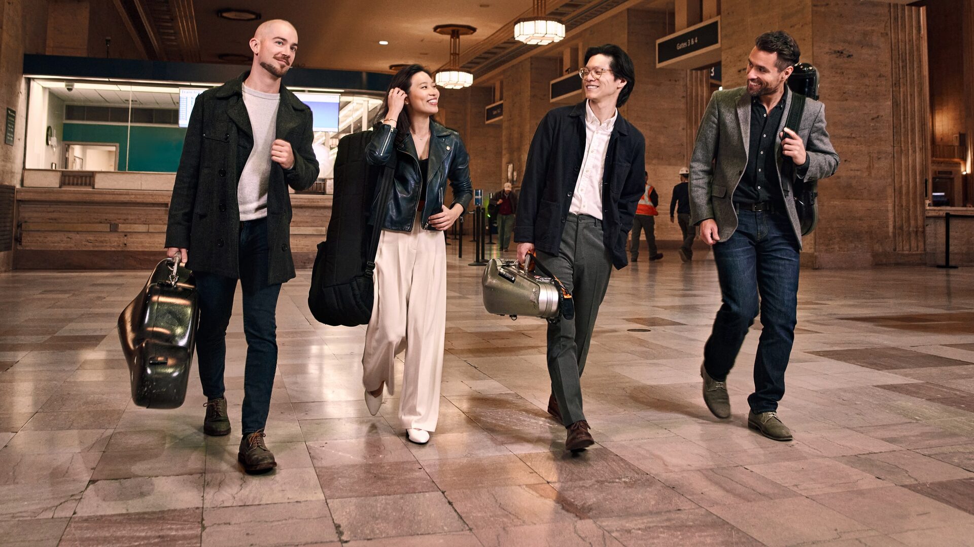 The Dover Quartet walking through a train station with their instruments